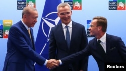 Presiden Turki Tayyip Erdogan dan PM Swedia Ulf Kristersson berjabat tangan disaksikan Sekretaris Jenderal NATO Jens Stoltenberg sebelum pertemuan puncak NATO, di Vilnius, Lithuania, Senin 10 Juli 2023. 