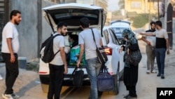 People unload luggage upon arriving at a house sheltering families of Lebanese refugees who were evacuated from Beirut's southern suburbs due to Israeli bombardment, in the city of Hilla in Iraq's central Babylon province, Oct. 9, 2024. 