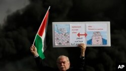 A Palestinian holds a poster depicting Israeli Prime Minister Benjamin Netanyahu, left, and U.S. Secretary of State Mike Pompeo as clashes with Israeli troops broke out at checkpoint Beit El near the West Bank city of Ramallah, Nov. 26, 2019.