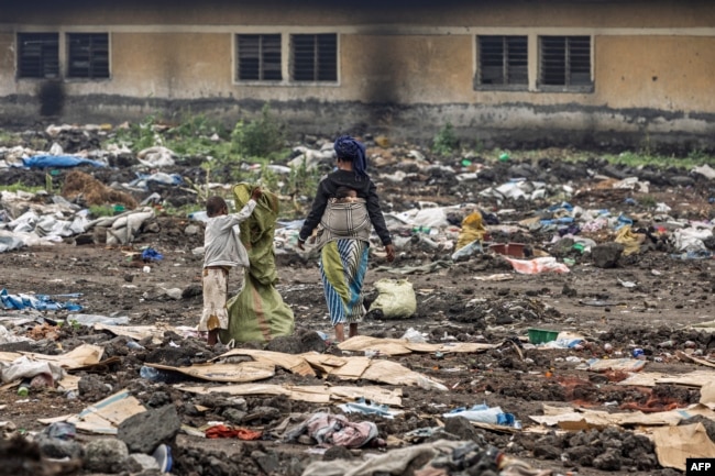 A woman accompanied by her children picks through discarded items in the area where a camp for internally displaced persons once stood before it was destroyed, in Goma on Feb. 1, 2025.