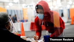 FILE - A young voter fills out a ballot with assistance from a poll worker at a polling station at the Midtown Center shopping mall in Milwaukee, on the first day of in-person voting in Wisconsin, October 20, 2020.