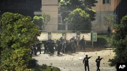 Riot policemen shield themselves from rocks thrown by protesters at the entrance to the Jinko solar factory in Haining, Zhejiang province, September 17, 2011.