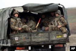 Ethnic Armenian soldiers sit in a military truck on a road during the withdrawal of troops from the separatist region of Nagorno-Karabakh, Nov. 19, 2020.