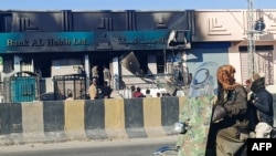 Commuters ride past a bank set ablaze by militants in the Kalat district of Pakistan's Balochistan province on Feb. 1, 2025. Eighteen soldiers were killed in the attack, police and the military said.