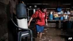 A woman walks into her house, flooded during the passage of Hurricane Iota in Siuna, Nicaragua, Nov. 17, 2020.