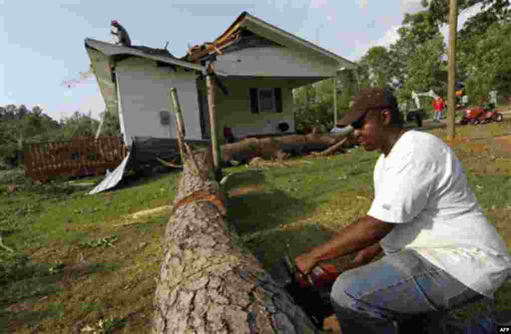 Undeon Hardy cuts a section of pine that damaged the Longino, Miss., home of John Mullins following a tornado touchdown that caused several deaths nearby Wednesday, April 27, 2011. Several tornadoes hit in the state resulting in number of deaths. (AP Pho