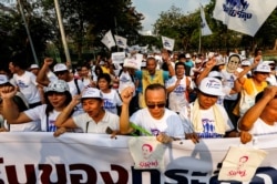 Supporters of Thailand’s Prime Minister Prayut Chan-ocha hold a banner and signs as they walk to show their support for the government at a park in Bangkok, Jan. 12, 2020.