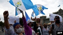 Manifestantes ondea banderas de Guatemala para exigir al presidente de Guatemala, Alejandro Giammattei, que ponga fin a las medidas de confinamiento impuestas desde marzo debido a la pandemia. Mayo 28 de 2020. 