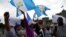 Manifestantes ondea banderas de Guatemala para exigir al presidente de Guatemala, Alejandro Giammattei, que ponga fin a las medidas de confinamiento impuestas desde marzo debido a la pandemia. Mayo 28 de 2020. 
