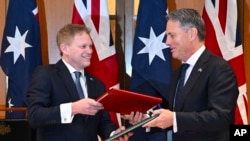 2024年3月21日，英国国防大臣格兰特·沙普斯（Grant Shapps，左）和澳大利亚国防部长理查德·马勒斯（Richard Marles）在澳大利亚议会交换新签署的国防和安全合作协议。