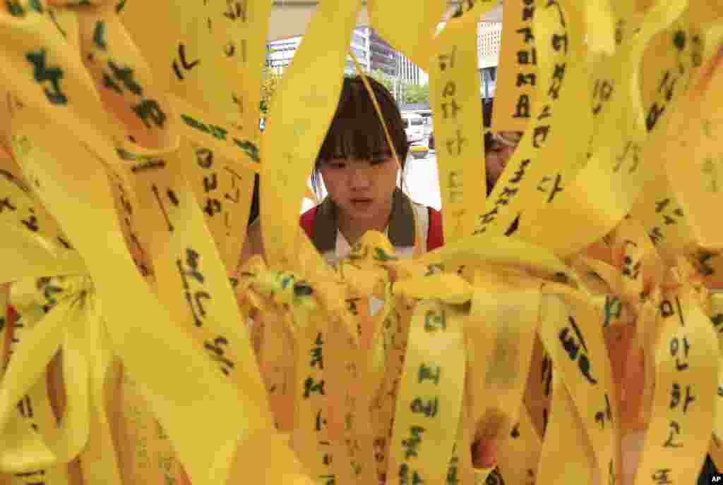 Seorang siswi sekolah menengah membaca pesan-pesan yang tertulis di atas pita bagi korban kapal Sewol yang tenggelam di sebuah altar memorial di Seoul, Korea Selatan (15/6). (AP/Ahn Young-joon)