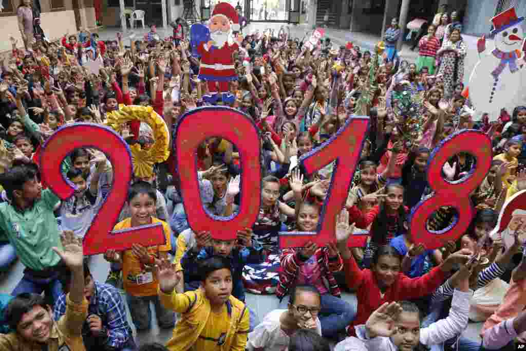 2017年12月30日，在印度艾哈迈达巴德（Ahmadabad）的一所学校，学童抬着圣诞老人像，欢呼2018年到来。