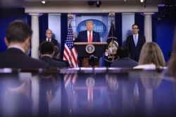 FILE - President Donald Trump speaks, flanked by White House economic advisor Larry Kudlow, left, and Treasury Secretary Steven Mnuchin, during a press briefing on the U.S. economy, at the White House in Washington, July 2, 2020.