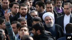 Un homme iranien, à gauche, prend une selfie en essayant d'avoir le président Hassan Rouhani, juste avec le turban blanc, sur la photo lors d'un rassemblement commémorant le 37e anniversaire de la révolution islamique, à la rue Azadi (Freedom) à Téhéran, en Iran , 11 février 2016. 