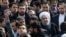 An Iranian man, at left, takes a selfie while trying to have President Hassan Rouhani, right with white turban, in his picture in a rally commemorating the 37th anniversary of the Islamic revolution, in Tehran, Feb. 11, 2016.
