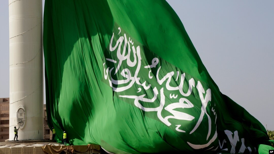 Pekerja menurunkan bendera raksasa Saudi, yang berukuran 49,5 meter kali 33 meter untuk pemeliharaan mingguan, di landmark Jiddah, di King Abdullah Square. (Foto: AP)