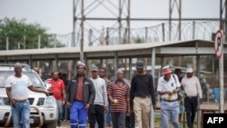 FILE - Two miners (2nd R and 4th R) look on after they resurfaced, because of medical conditions, from the underground protest at the Bafokeng Rasimone Platinum Mine near Rustenburg on December 19, 2023.