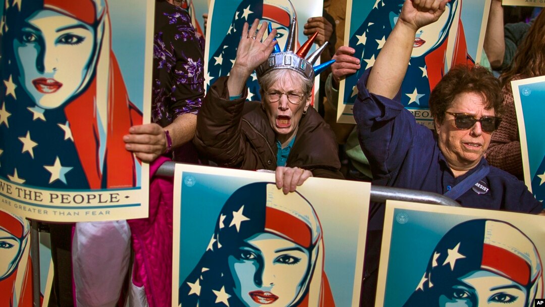 FILE - In this Feb. 19, 2017, photo, people carry posters during a rally against President Donald Trump's executive order banning travel from six Muslim-majority nations, in New York's Times Square.