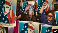 FILE - Protesters carry posters during a rally against President Donald Trump's executive order banning travel from seven Muslim-majority nations, in New York's Times Square, Feb. 19, 2017.