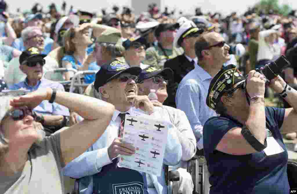 World War II veterans and their families watch as dozens of WWII-era military airplanes fly over the National World War II Memorial in Washington, D.C., May 8, 2015, during the Arsenal of Democracy World War II Victory Capitol Flyover to commemorate the 70th anniversary of Victory in Europe (VE) Day.