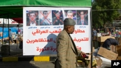 A protester walks past a poster with defaced pictures of Iraqi politicians and Arabic that reads, "Wanted by the Iraqi people for inciting against the demonstrators and for defacing the revolution's image," in Baghdad, Iraq, Dec. 28, 2019.