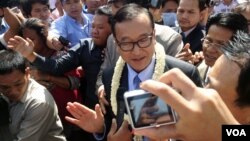  ທ່ານ Sam Rainsy ຫົວໜ້າພັກກູ້ຊາດກໍາປູເຈຍ ກ່າວຕໍ່ສື່ມວນຊົນ ຢູ່ນອກປະຕູເຂົ້າສະໜາມບິນກ່ອນທີ່ທ່ານຈະເລີ້ມຍ່າງໄປໃນນະຄອນພະນົມເປັນ ຂອງກໍາປູເຈຍໃນວັນທີ 16 ສິງຫາ 2013. (Robert Carmichael for VOA)