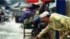 A Cambodian amputee beggar is given money by a passerby while wading in the street flood in Phnom Penh.