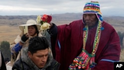 El líder espiritual José Mamani bendice a una persona con agua en un ritual por el Año Nuevo Andino tras recibir los primeros rayos de sol del día en el cerro Turriturrini a las afueras de Huarina, Bolivia, el viernes 21 de junio de 2024. 