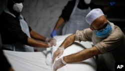 Jenazah Mohammad Altaf, 48 tahun, yang meninggal karena COVID-19, sedang dikafani oleh para petugas di Layanan Pemakaman Muslim Al-Rayaan, di Brooklyn, New York, 17 Mei 2020. (Foto: John Minchillo/AP, arsip)