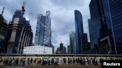 FILE - Office workers walk to the train station during evening rush hour in the financial district of Singapore, March 9, 2015. 