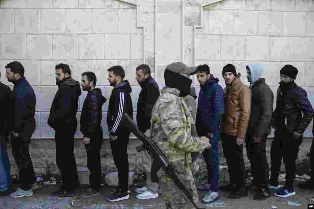 Members from ousted President Bashar al-Assad&#39;s Syrian army line up to register with rebels as part of a &quot;identification and reconciliation process&quot; at a army compound in Latakia.