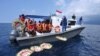 People throw flowers and petals with names of the sunken KRI Nanggala-402 submarine crew members from the boat during a prayer at the sea near Labuhan Lalang, Bali, Indonesia.