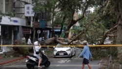 Orang-orang berjalan melintas di area yang porak-poranda akibat Badai Kong-rey di Taipei, Taiwan, Jumat, 1 November 2024. (Foto: Chiang Ying-ying/AP Photo)