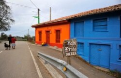 FILE - Villagers stand in front of decorated houses in the small village of Sietes, northern Spanish region of Asturias, Oct. 19, 2009.