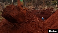 A worker stands beside an excavator digging for ore at Mobi Jaya Persada's nickel mining area at Dampala village in Marowali, central Sulawesi, Indonesia, Jan. 12, 2014.