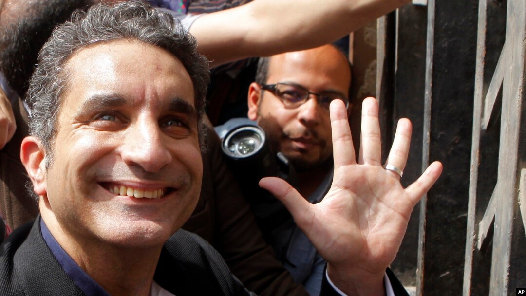 Egyptian television satirist Bassem Youssef waves to his supporters as he enters Egypt's state prosecutors office to face charges for allegedly insulting Islam and the country's leader, in Cairo, Mar. 31, 2013.