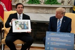 President Donald Trump listens as Gov. Ron DeSantis, R-Fla., talks about the coronavirus response during a meeting in the Oval Office of the White House, April 28, 2020, in Washington.