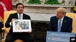 Predsjednik Donald Trump sluša kako guverner Ron DeSantis, R-Fla., govori o odgovoru na koronavirus tokom sastanka u Ovalnom uredu Bijele kuće, u utorak, 28. aprila 2020., u Washingtonu. (AP Photo/Evan Vucci)