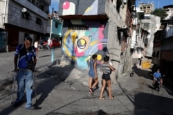 People walk pass a mural painted by Fabian Solymar in Petare slum, in Caracas, Venezuela, Aug. 7, 2019.