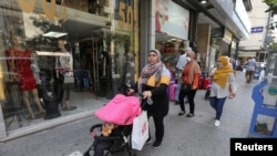 Women walk past open shops, as Lebanon is gradually reopening its economy following a four-day shutdown imposed to curb the spread of coronavirus disease (COVID-19) in Hamra street in Beirut, May 18, 2020.