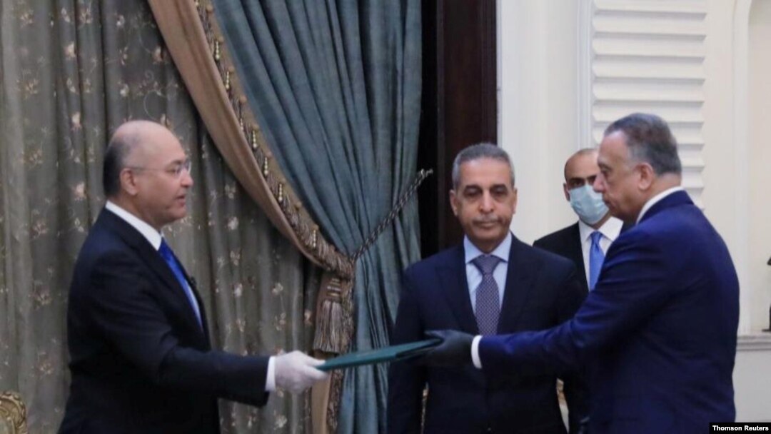 Iraq's President Barham Salih, left, instructs newly appointed Prime Minister Mustafa al-Kadhimi in Baghdad.