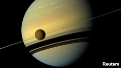 Titan, Saturn's largest moon appears before the planet as it undergoes seasonal changes in this natural color view from NASA's Cassini spacecraft in this handout released by NASA August 29, 2012. (REUTERS/ NASA/JPL-Caltech/SSI)