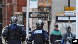 Riot police chase alleged looters during civil disturbances in Manchester, England, Aug. 9, 2011