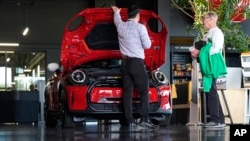 FILE - A salesperson shows an unsold 2024 Cooper SE electric hardtop to a prospective buyer at a Mini dealership on May 1, 2024, in Highlands Ranch, Colorado. On May 3, a U.S. government report said employers added 175,000 jobs in April.