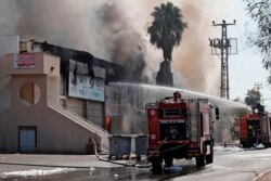 FILE - Israeli firefighter trucks douse a burning factory in the southern Israeli town of Sderot, after it was reportedly hit with rockets fired from the Gaza Strip, Nov. 12, 2019.
