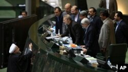 FILE - Iranian President Hassan Rouhani, left, presents a draft of the country's new budget and sixth development plan to the parliament speaker in an open session of parliament, in Tehran, Iran, Jan. 17, 2016.