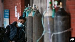 FILE - A COVID-19 patient receives oxygen outside an emergency ward at a government-run hospital in Kathmandu, Nepal, May 13, 2021. 