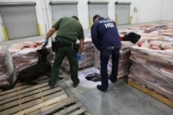 FILE - Investigators look at the entrance to a drug-smuggling tunnel in a warehouse in Otay Mesa in Southern California, Nov. 15, 2011.