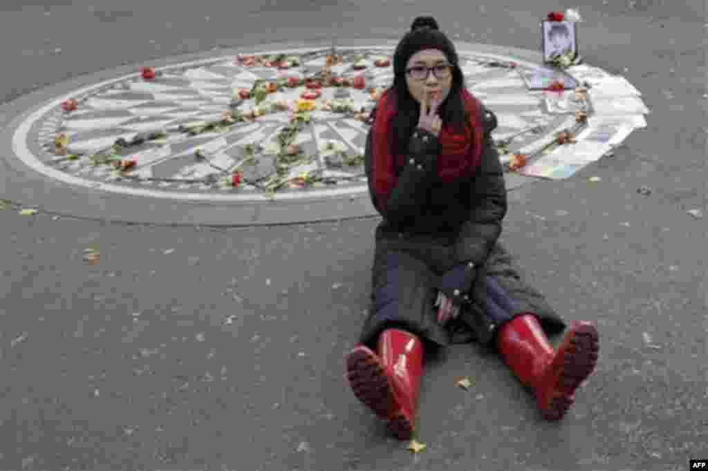 Chi Chi Yao, of Taiwan, makes a peace sign as she poses for photos at Strawberry Fields in New York's Central Park, Tuesday, Dec. 7, 2010 in New York. Wednesday marks 30 years since John Lennon was murdered outside his New York apartment, triggering a wav