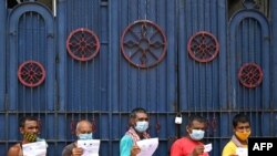 Workers hold documents as they wait for their turn to receive the first dose of Covishield vaccine in a passenger bus converted into a mobile vaccination center in Kolkata, India.